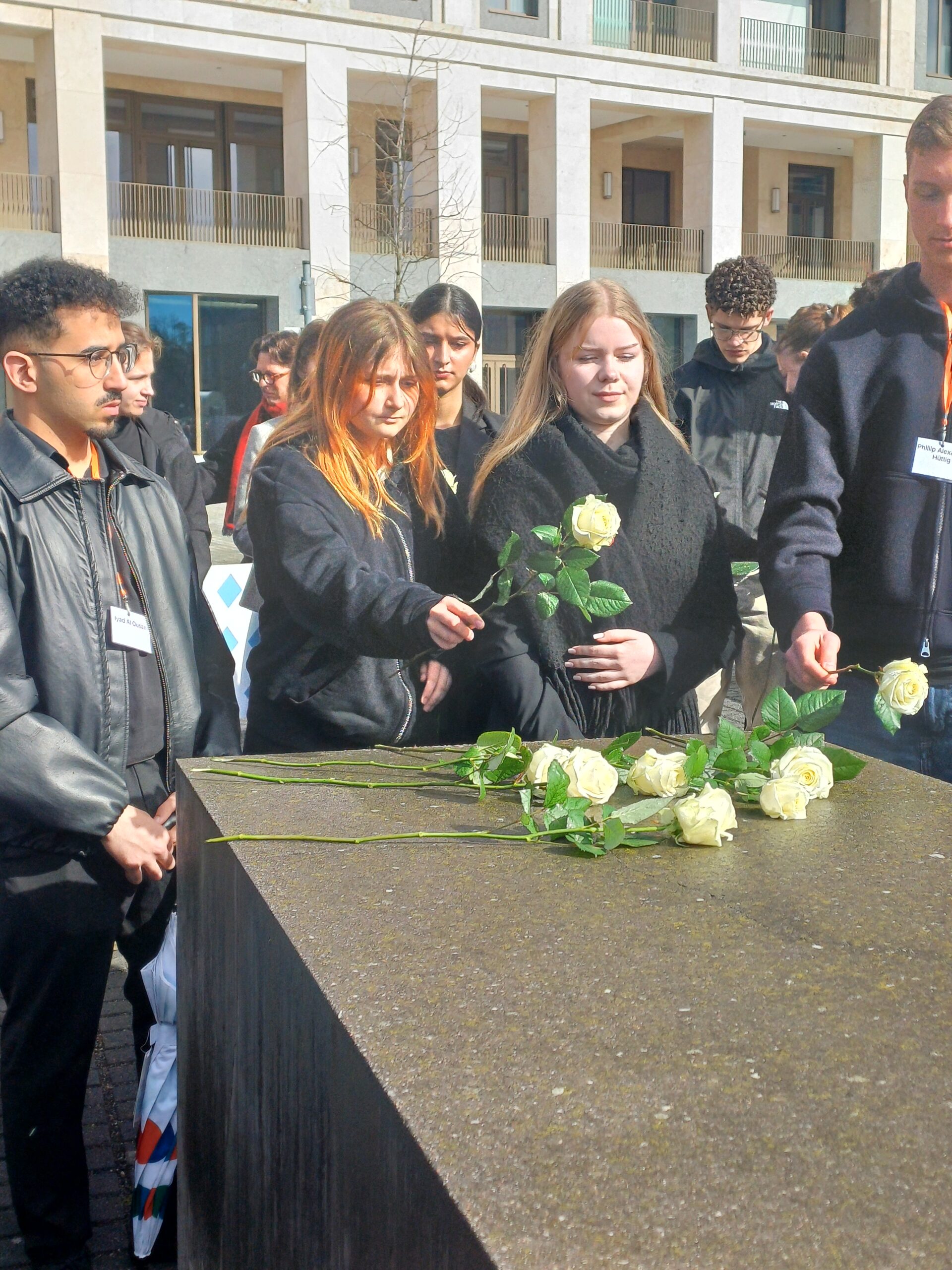 Jugendliche legen weiße Rosen nieder.